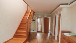 A wooden staircase leading to a hallway with wooden flooring and a wooden cabinet. - Wyvill House (Scarborough)