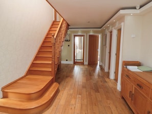 A wooden staircase leading to a hallway with wooden flooring and a wooden cabinet.
