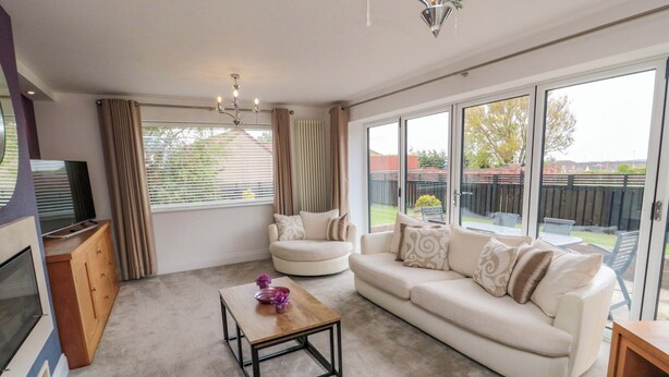 A spacious living room with a sofa, a coffee table, and a TV. - Wyvill House (Scarborough)