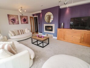 A modern living room with a sofa, coffee table, TV, and decorative items.