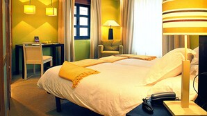 Et hotelværelse med to senge, et skrivebord, en stol og en lampe.