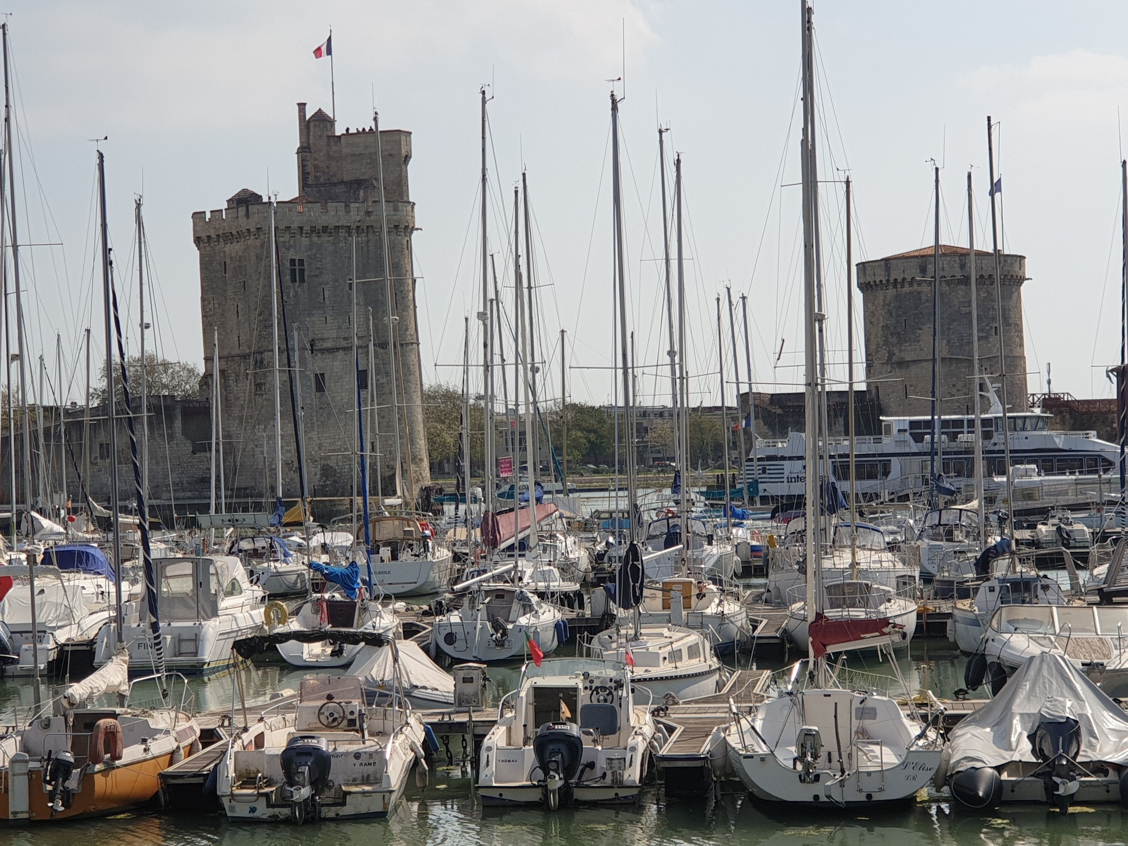 Un puerto deportivo con varias embarcaciones amarradas, una torre destacada y un edificio con cúpula.