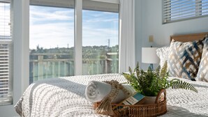 A neatly made bed with a rolled towel, a woven basket with a plant, and a book on a white textured bedspread. - 300 Ocean Mile: 150 Steps to Beach! Kid Friendly, 2 Pools, Bikes! (Saint George Island)