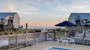 A pool area with a view of the beach, wooden deck, and a sign indicating pool rules. - 300 Ocean Mile: 150 Steps to Beach! Kid Friendly, 2 Pools, Bikes! (Saint George Island)