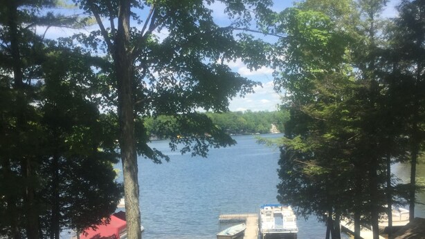 Un espace de pique-nique au bord du lac, équipé d’un banc en bois, d’une table de pique-nique et d’un petit quai avec des bateaux.