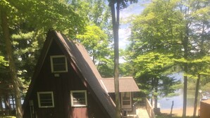 Une cabane avec un toit en pente, une petite terrasse et une vue sur un lac.