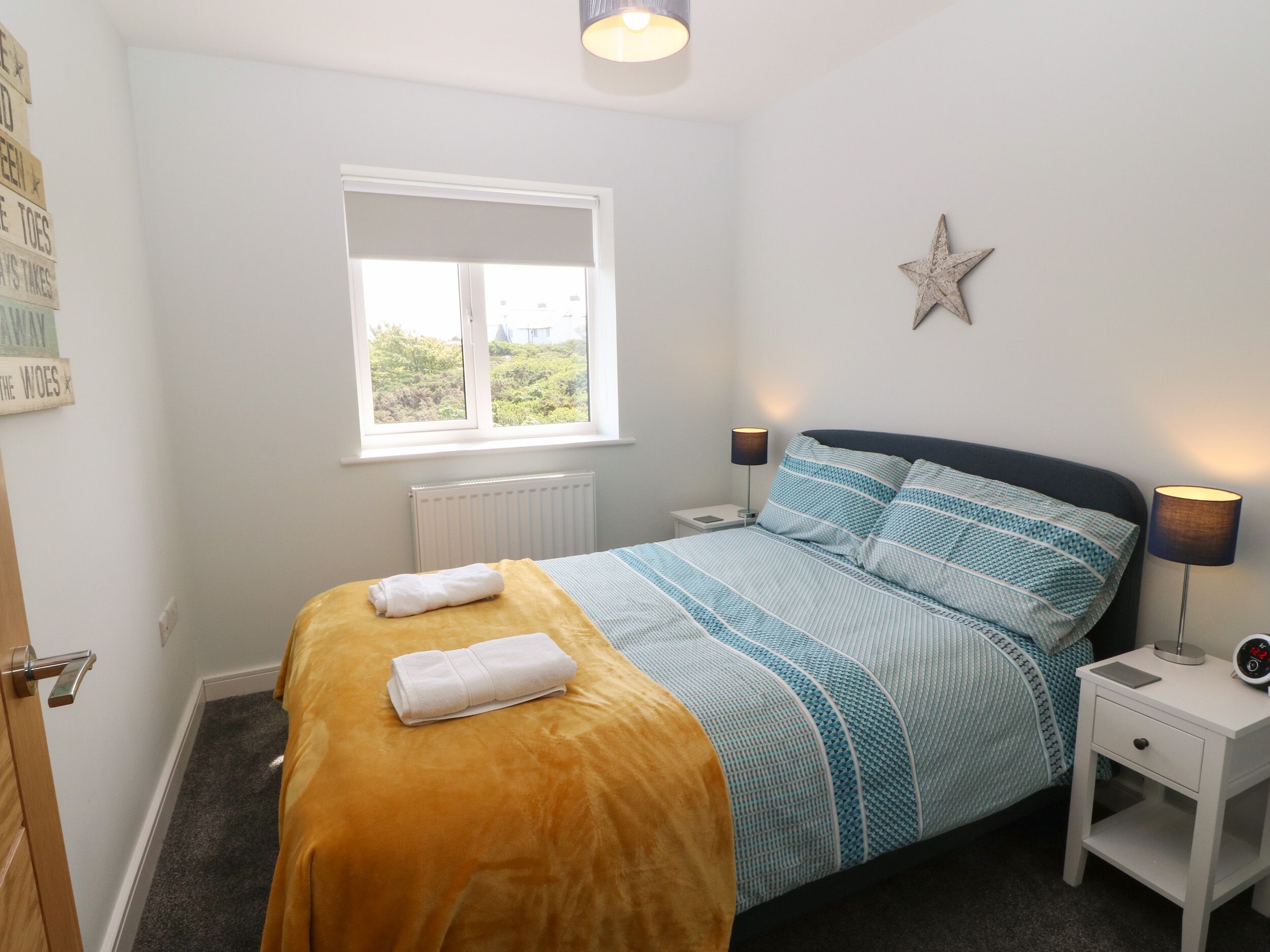 A bedroom with a bed, bedside lamps, a star decoration, and a window.