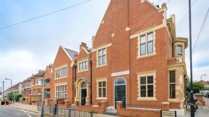 A row of red brick houses with a sign indicating a library and gardens. - Unique 2 Bedroom Penthouse Apartment in Kensal Rise (London)