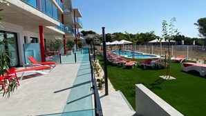 A modern hotel with a pool area, outdoor seating, and a clear view of the surrounding landscape. - Azahar Beach Apartments (Alcala de Xivert)