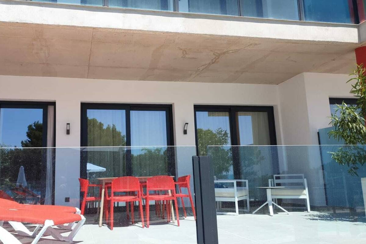 A modern building with large windows, a glass balcony, and outdoor seating.