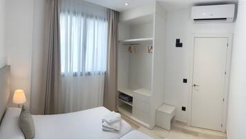 Una habitación de hotel con cama, lámpara de noche, armario y aire acondicionado.