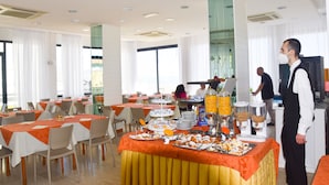Comedor de hotel con varias mesas, sillas y una barra de buffet.
