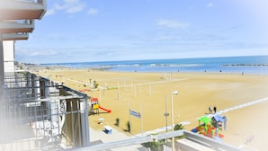 Vista a la playa desde un balcón con un parque infantil y un cartel que dice 'Bucanilla'.