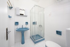 A modern bathroom with a glass-enclosed shower, a pedestal sink, and a toilet.