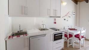 Eine kompakte Küche mit weißen Schränken, einem eingebauten Geschirrspüler, einer Mikrowelle und einem kleinen Backofen.