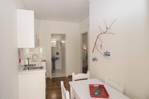 A modern kitchen with white cabinets, a sink, and a dining area with a table and chairs.