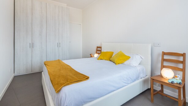 Un dormitorio con cama, mesita de noche, silla de madera y armario.