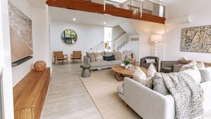 A spacious living area with a high ceiling, a staircase, and a view of the outdoors. - Sandy Point Beach House - On The Waterfront.  Mid Week Stay Special Is Now On. (Corlette)