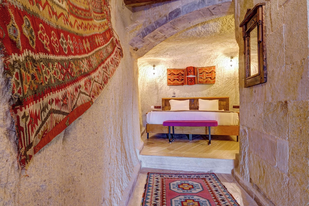 A narrow hallway with a bed, a rug, and a tapestry.