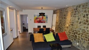 Una sala moderna con un sofá modular, una mesa de comedor y una pared de acento de piedra.
