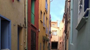 Una estrecha calle adoquinada flanqueada por edificios coloridos con balcones y puertas.