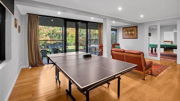 Een ruime kamer met een tafeltennistafel, een bank en een biljarttafel.