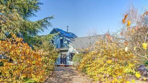 Een huis met een blauw dak, omgeven door bomen met herfstbladeren.