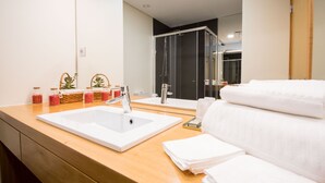 A modern bathroom with a large white sink, a glass shower enclosure, and a wooden vanity. - Bugalha My Loft Douro 9 (Peso da Régua)