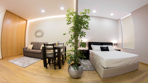 A modern bedroom with a bed, a sofa, a dining table, and a potted plant. - Bugalha My Loft Douro 9 (Peso da Régua)