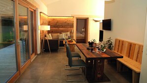 A modern kitchen with a wooden dining table, bar stools, and a bench. - Ferienhaus mit Sauna am Waldrand (Kärnten)