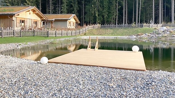 A wooden cabin with a dock extending into a calm lake, surrounded by a forested area. - Ferienhaus mit Sauna am Waldrand (Kärnten)