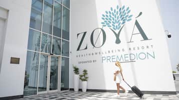 A modern building with a large glass entrance, a logo for Zoya Health & Wellness Resort, and a sign indicating it is operated by Premedian.