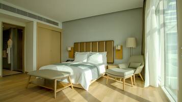 Een moderne hotelkamer met een groot bed, twee nachtkastjes, een stoel en een groot raam.
