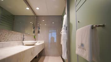A modern bathroom with a large sink, mirror, and towel rack.