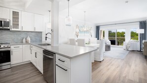 Una cucina moderna con mobili bianchi, un'isola grande e un'area da pranzo con arredi bianchi.