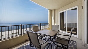 Ein Balkon mit Tisch und Stühlen mit Blick auf einen Strand und den Ozean.
