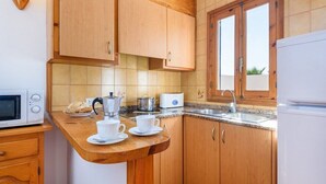 Une cuisine compacte avec des meubles de rangement en bois, un four à micro-ondes, une machine à café et un évier.