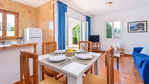 Un espace de vie compact comprenant un coin repas, une kitchenette et un coin salon avec un téléviseur.