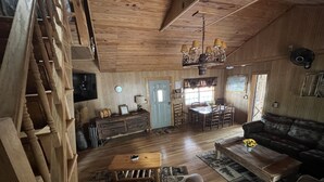 Un interior de madera con comedor, sofá y una escalera.