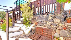 A stone staircase leading up to a wooden deck with a railing, surrounded by various plants and a stone wall. - Vacation apartment CASA LA ISLA, Tarajalejo, fiber optic internet (Tarajalejo)