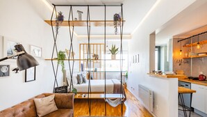 A modern living space with a sofa, a hanging plant, a bed, and a kitchen area. - Casa da Música 5th High (Porto)