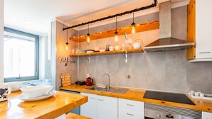 A modern kitchen with wooden countertops, a stainless steel sink, and hanging pendant lights. - Casa da Música 5th High (Porto)