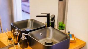 A modern bathroom with two black sinks, a mirror, and a small potted plant. - Casa da Música 5th High (Porto)
