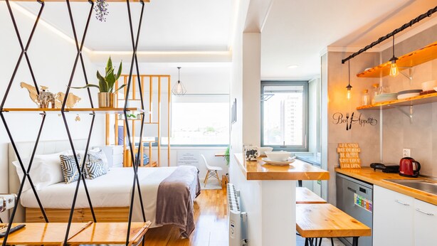 A modern, compact living space with a bed, a small seating area, a kitchenette, and a view of the city. - Casa da Música 5th High (Porto)