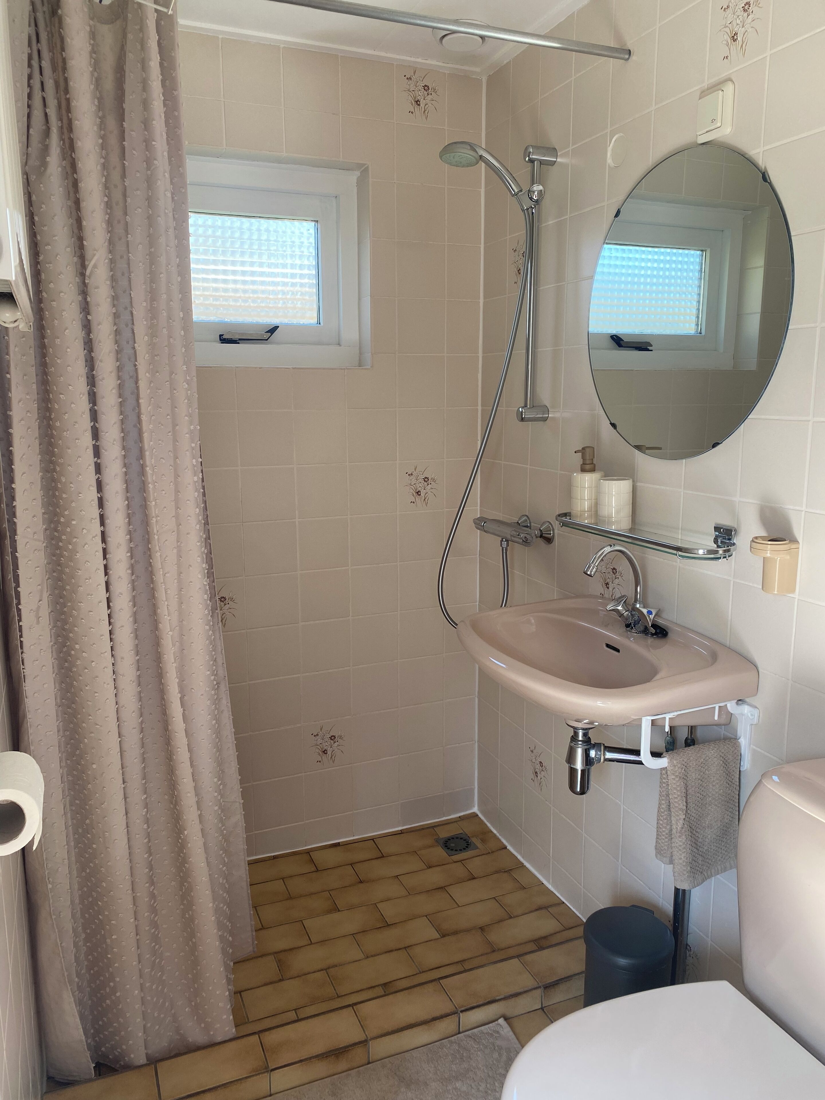 Ein Badezimmer mit Dusche, Waschbecken, Toilette und einem Fenster.