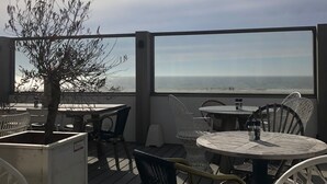Ein Außenbereich mit Tischen und Stühlen mit Blick auf ein Gewässer.