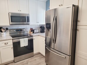 A modern kitchen with stainless steel appliances, including a microwave, oven, and refrigerator.