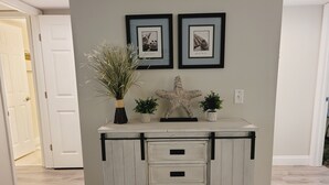A white dresser with black handles and three drawers, placed against a gray wall with two framed pictures above it. - Ocean view flat, poolside ( ground floor). Two  bedrooms, two baths. (St. Augustine)
