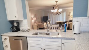 A modern kitchen with white cabinets, a stainless steel dishwasher, and a granite countertop. - Ocean view flat, poolside ( ground floor). Two  bedrooms, two baths. (St. Augustine)
