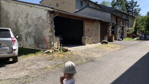 Uma criança em uma rua, em frente a um prédio com a porta da garagem aberta.